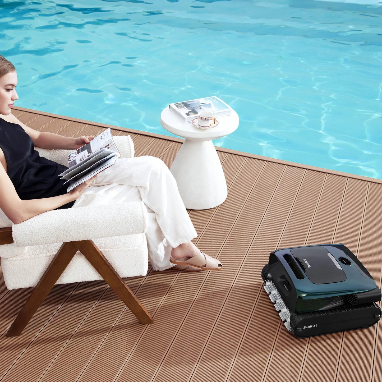 Beatbot AquaSense 2 Pro resting on a pool deck beside a woman reading in a chair