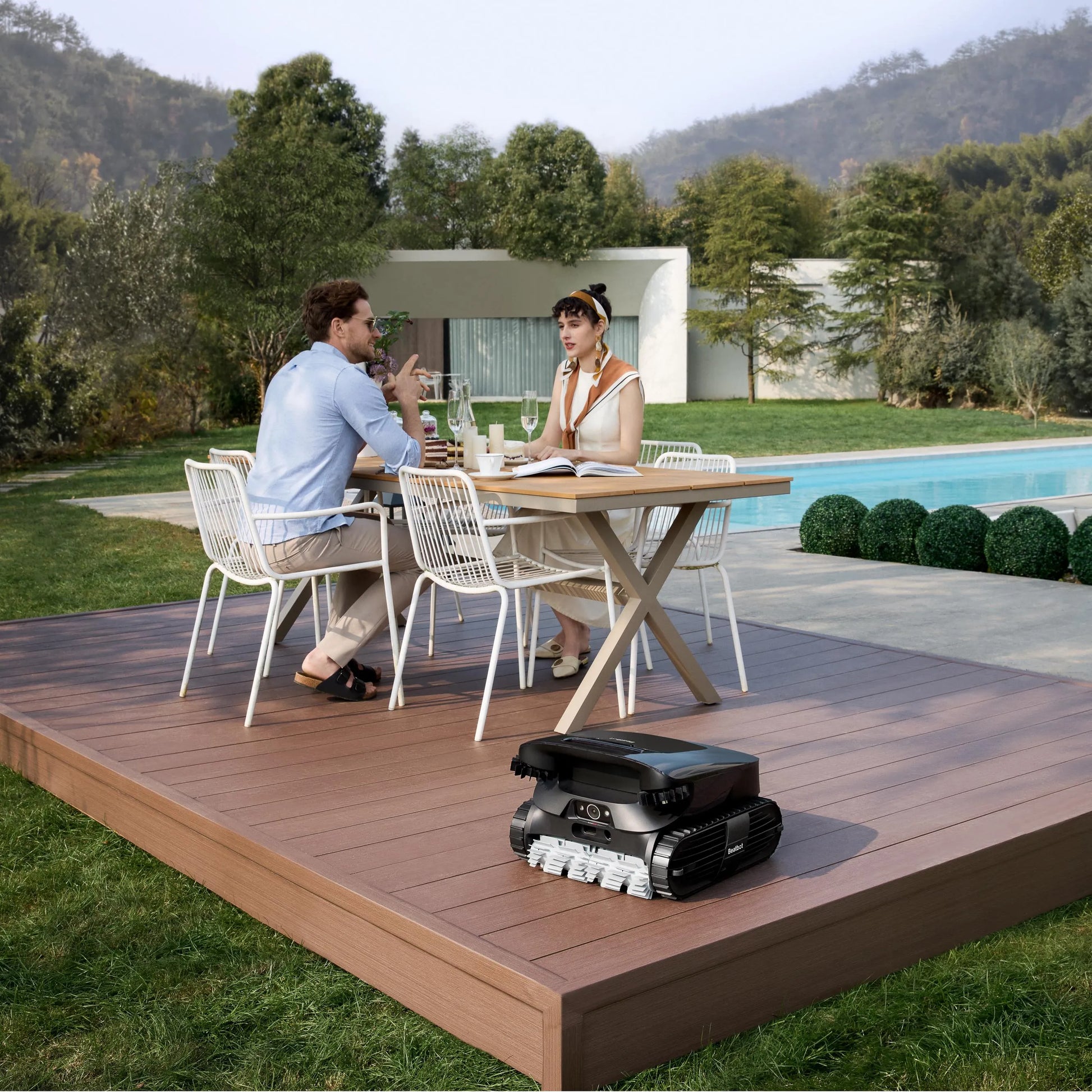 Beatbot AquaSense 2 Ultra on a poolside deck while two people dine outdoors