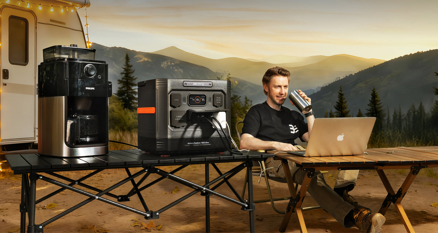 Jackery Explorer 1500 Ultra on a camp table powering a coffee maker and laptop near an RV