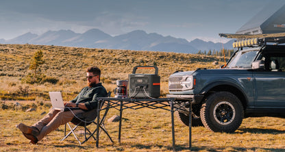 Jackery Explorer 1500 Ultra on a table beside an overland Ford Bronco during a mountain camp setup