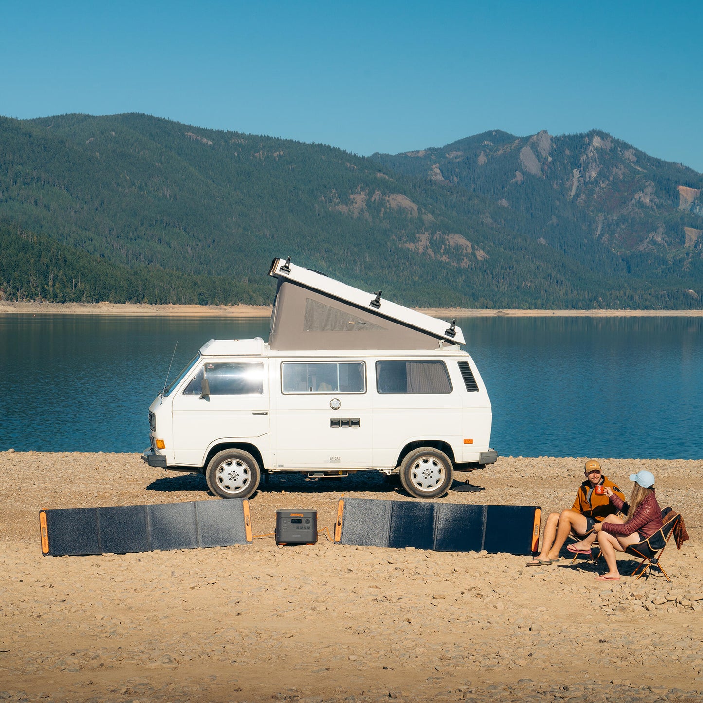 Two SolarSaga 200W panels and a power station set up on a beach beside a parked camper van