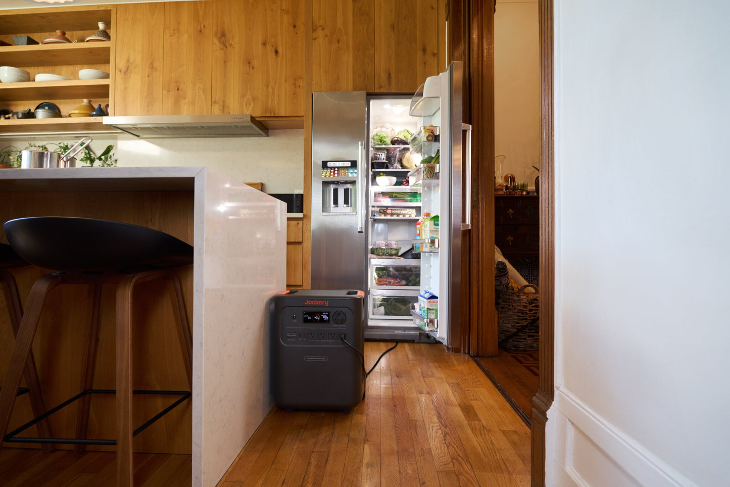 HomePower 3600 Plus next to an open refrigerator full of food in a wood-paneled kitchen