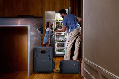 Father and daughter retrieving food from a fridge powered by HomePower 3600 Plus and Battery Pack during a storm, lightning visible through window