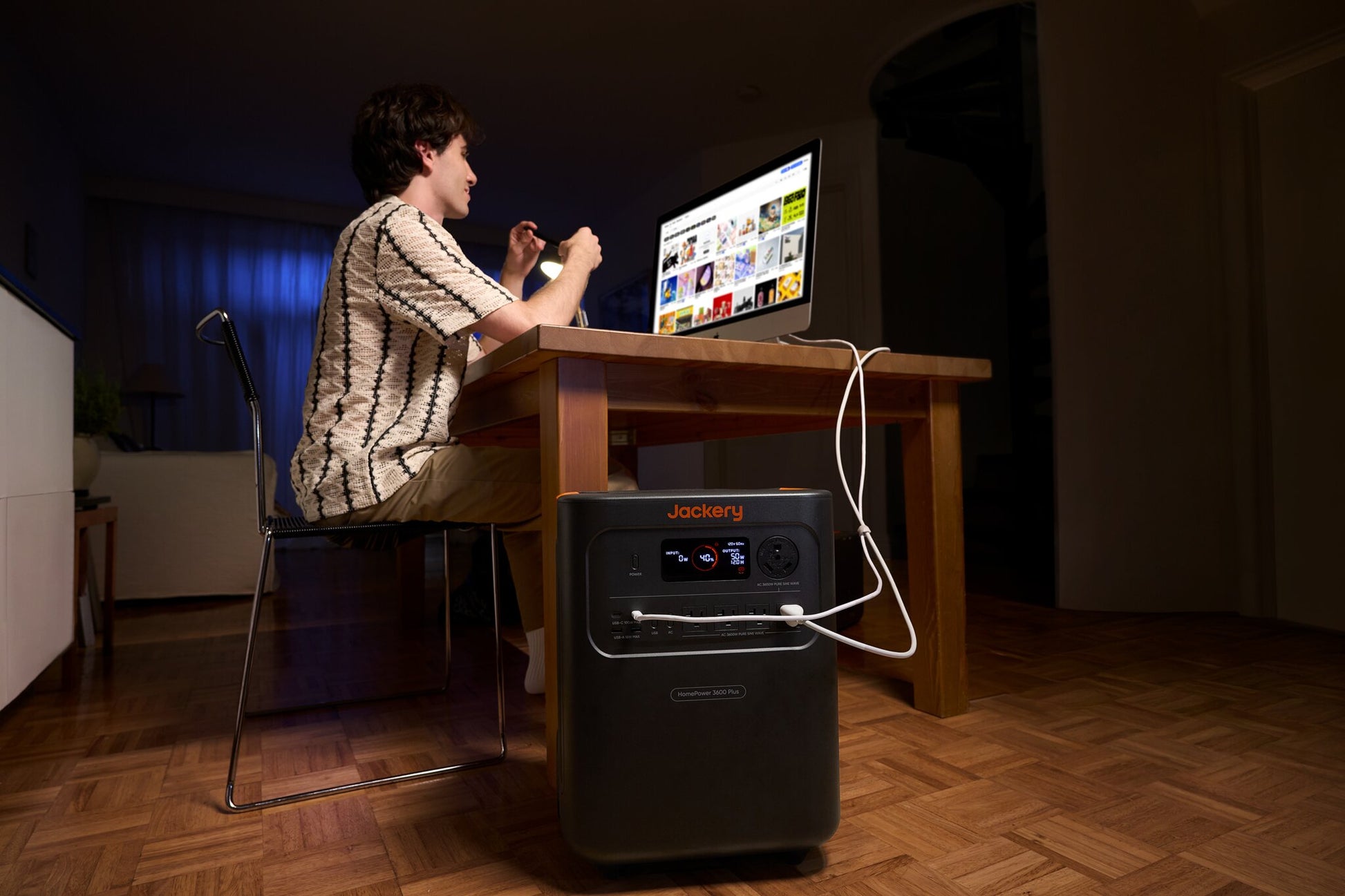Man working at a desk lit by a lamp powered by HomePower 3600 Plus during an evening power outage