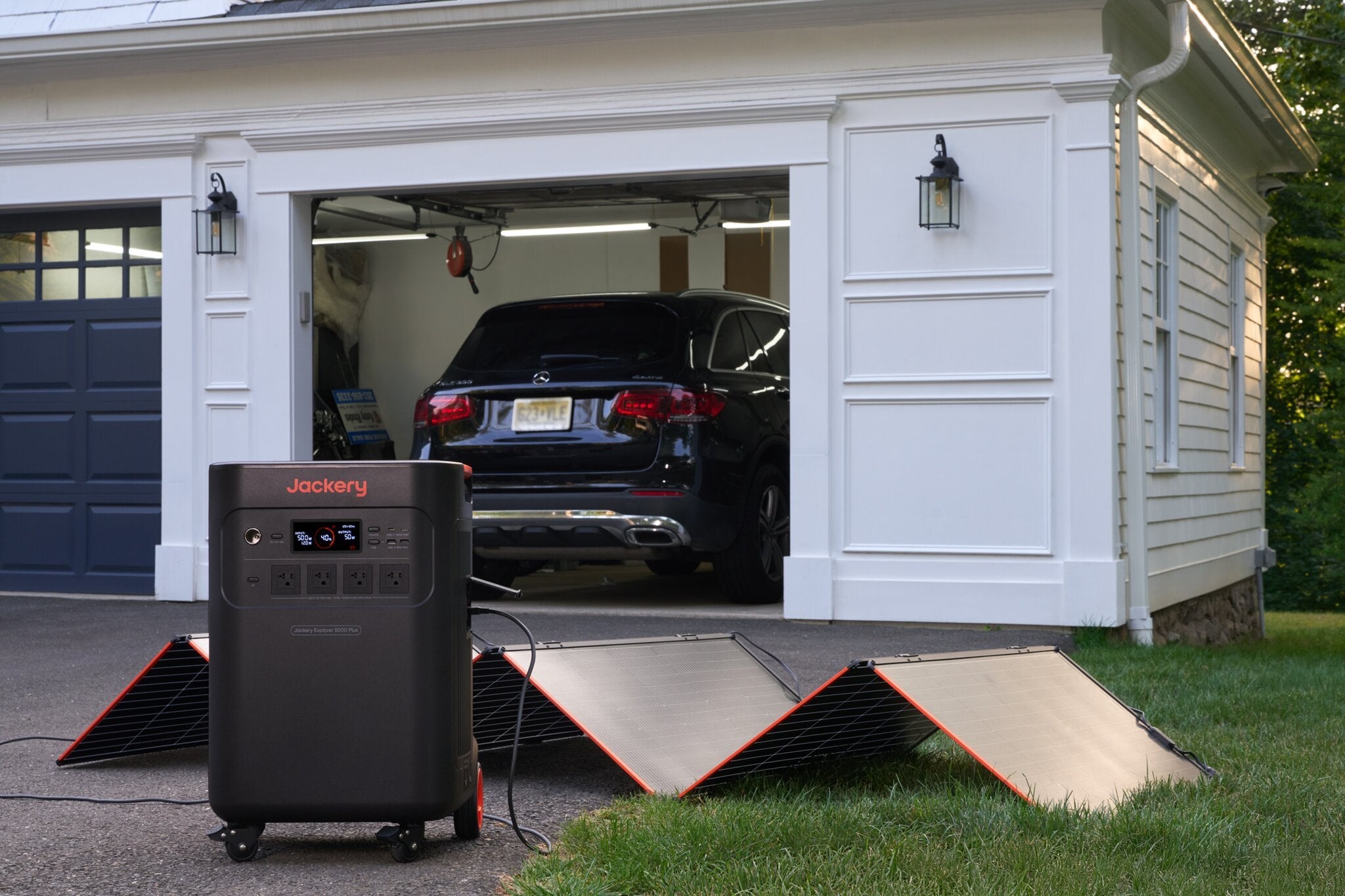 Jackery Explorer 5000 Plus charging from SolarSaga panels in a driveway at dusk