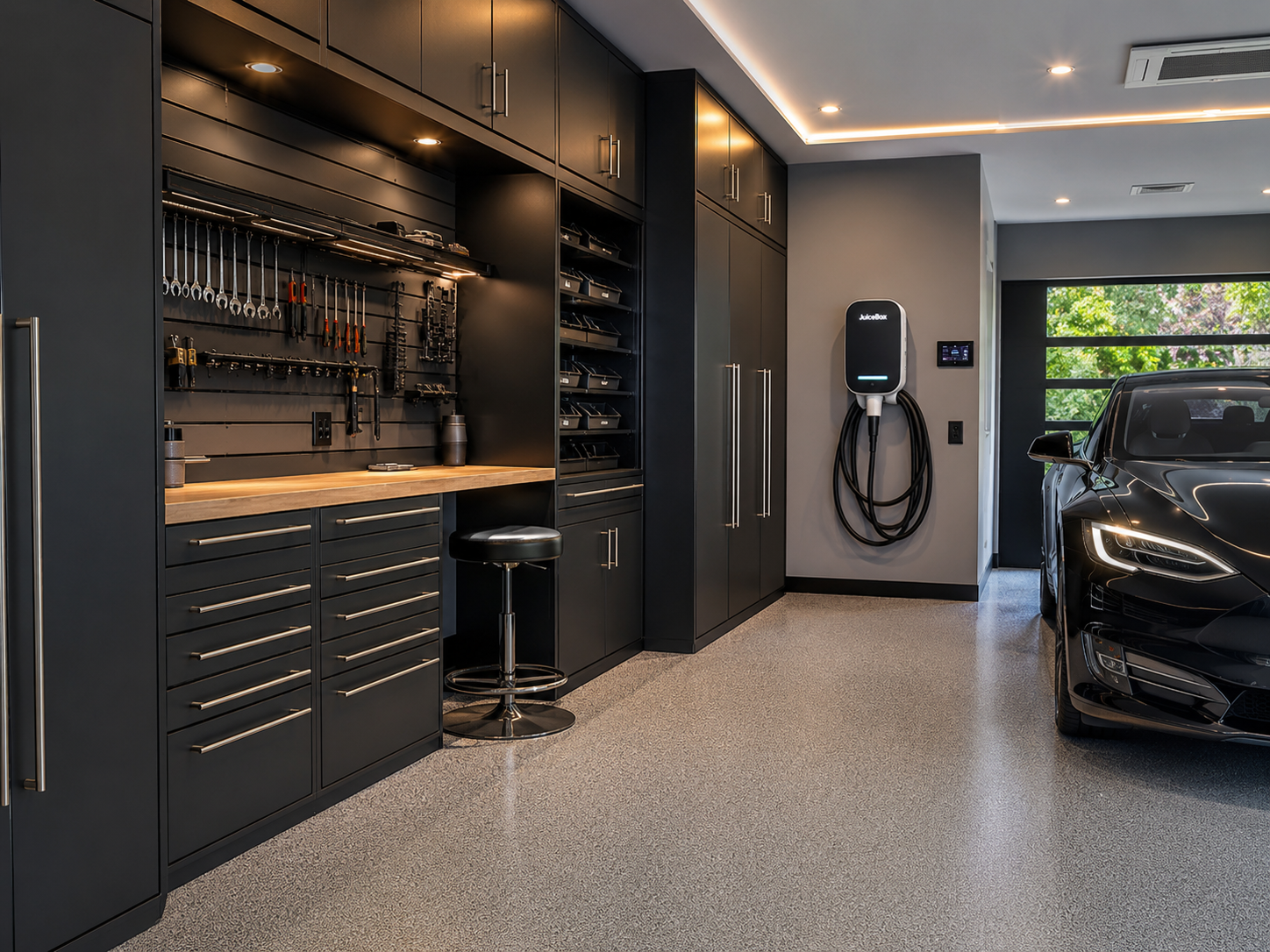 Dark modern garage workshop with black cabinetry, butcher-block bench, wall-mounted EV charger and an electric car parked in the bay